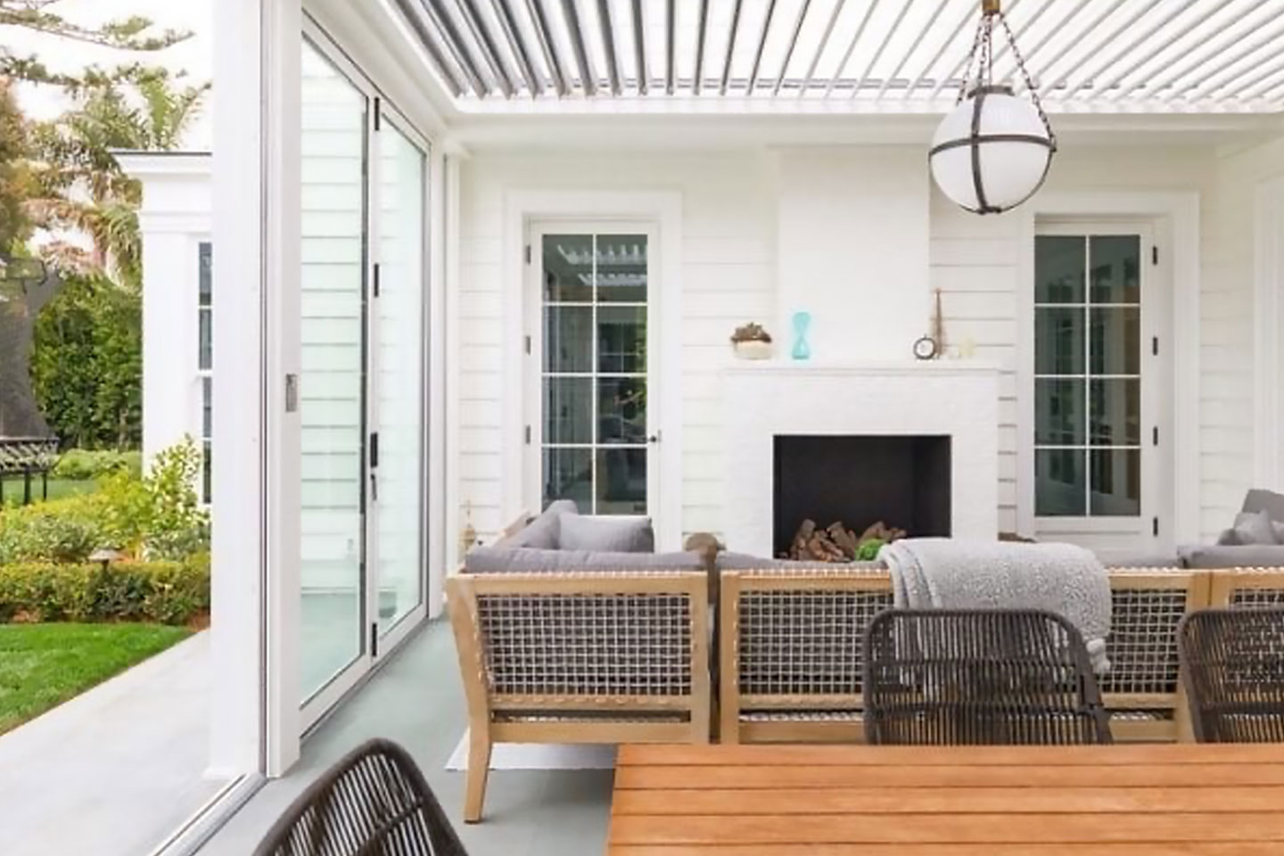 Automated louvered roof system on a white contemporary 3-season room with fireplace and glass walls, a custom solution by Decadent Outdoors.