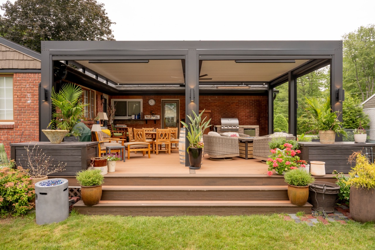 An outdoor patio space in Saratoga Springs that was designed by Decadent Outdoors showing a pergola, outdoor fan, and motorized screens as seen from the exterior of the structure.